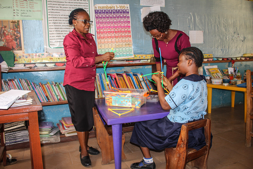 Teacher guiding students in a colourful classroom at Kate’s Rainbow Foundation Schools